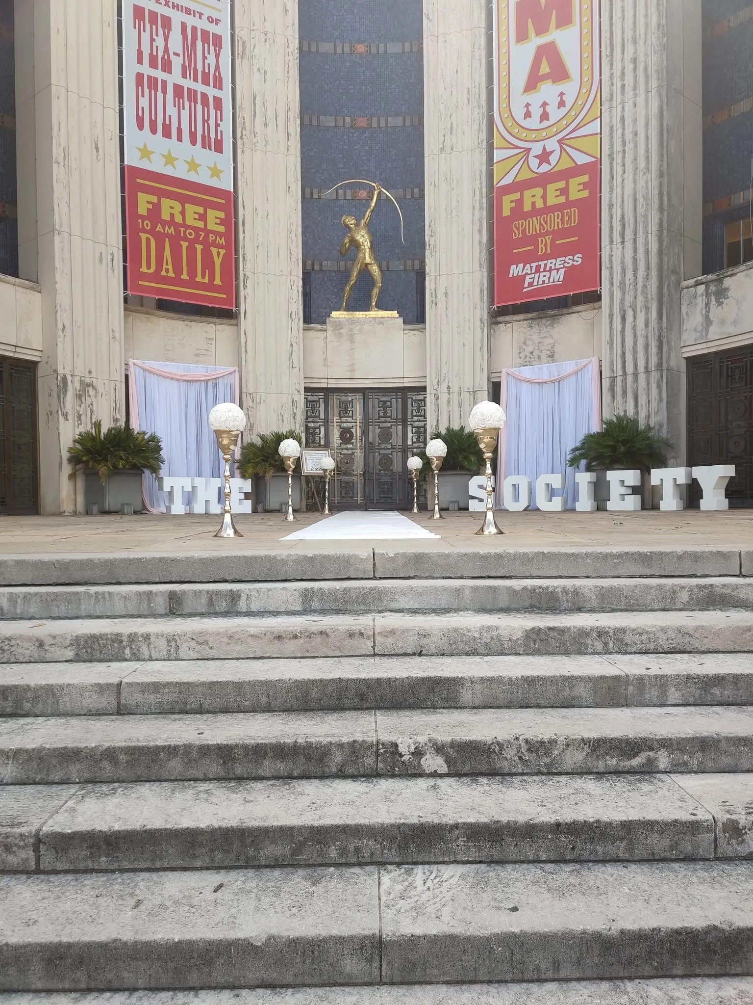 Outdoor venue-context entrance with white drapery and THE SOCIETY lettering